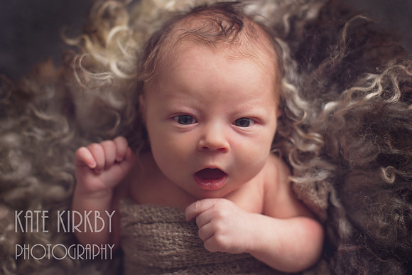 cute awake newborn on fluffy rug